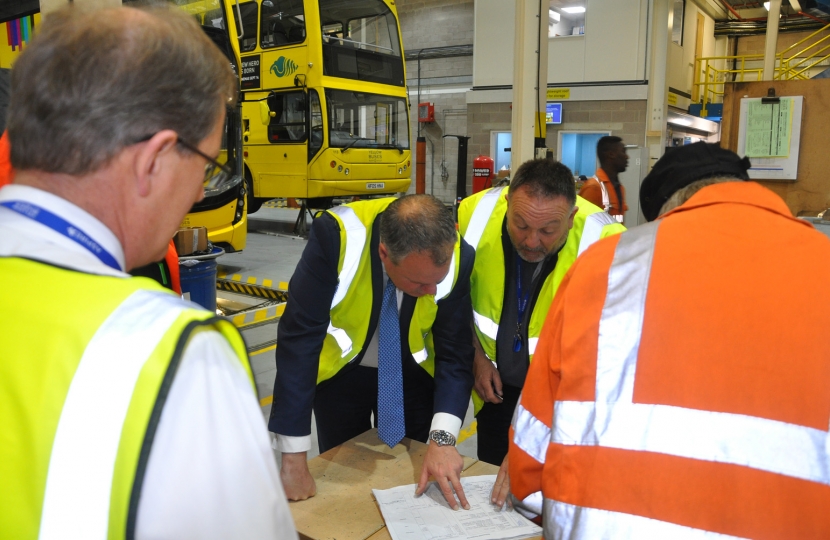 Conor pictured being shown a spreadsheet with a Yellow Buses mechanic and Andrew.