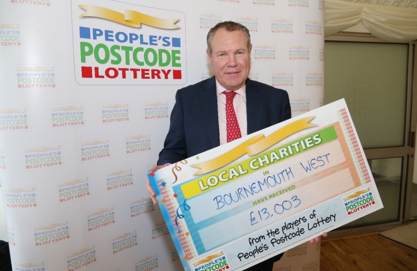 Conor pictured with a cheque showing the value of charitable donations in Borunemouth West from the People's Postcode Lottery.