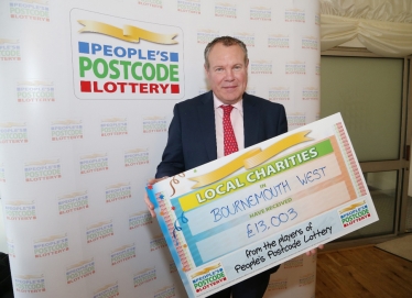 Conor pictured with a cheque showing the value of charitable donations in Borunemouth West from the People's Postcode Lottery.